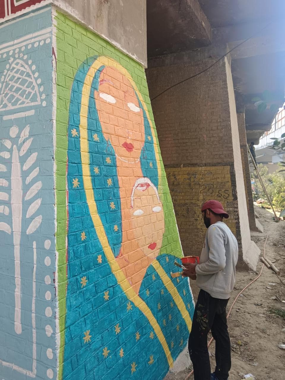 Artist painting mural under bridge