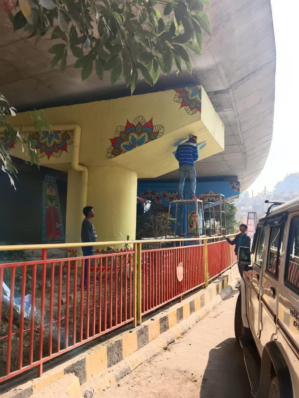Workers painting murals under flyover
